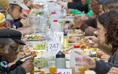 A number of people sharing food together at a long table