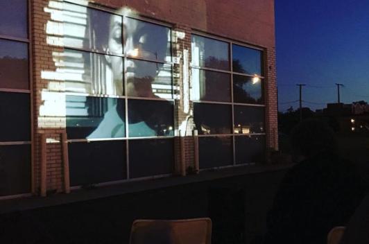 At night, a film is projected outside on a brick building.