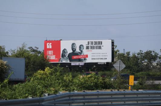 Alongside the road is a billboard in red and white featuring a family on it.