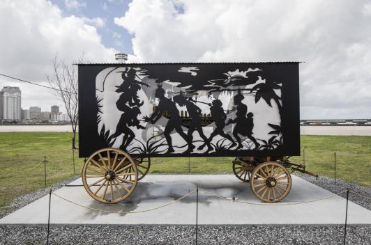 A carnival caravan with silhouettes of slaves and slave owners