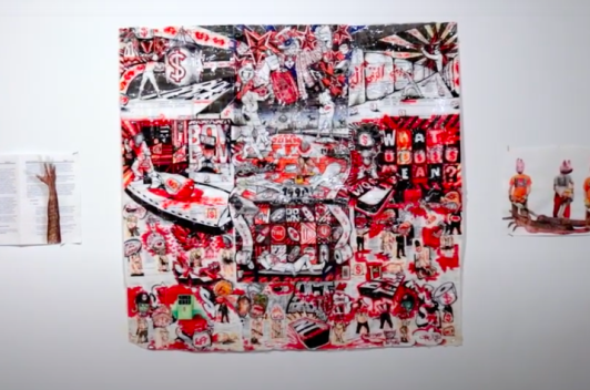 On a white gallery wall, a number of pieces of art hang on the wall. The pieces are mostly in red and black and featuring depictions of prison.