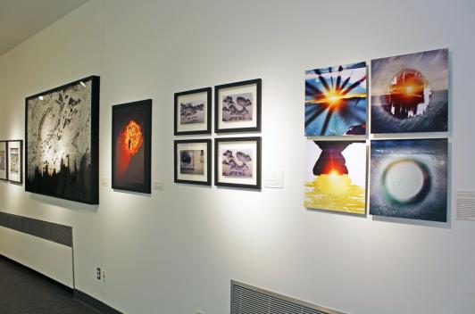 Photos of various weather occurrences on a white wall in a gallery.