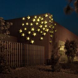 At dusk, the corner of a building is lit up with metal origami stars.
