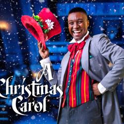 A person in a gray suit with a red vest, bow tie and hat, smiles in a wintry scene. The words "A Christmas carol" are below him.