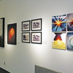 Photos of various weather occurrences on a white wall in a gallery.