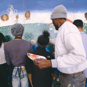 Various people working on a mural depicting a valley with happy faces and green grass