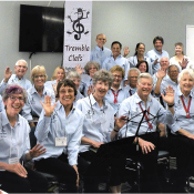 A choir smiling and all in light blue shirts