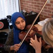 a student with a violin being taught by an instructor