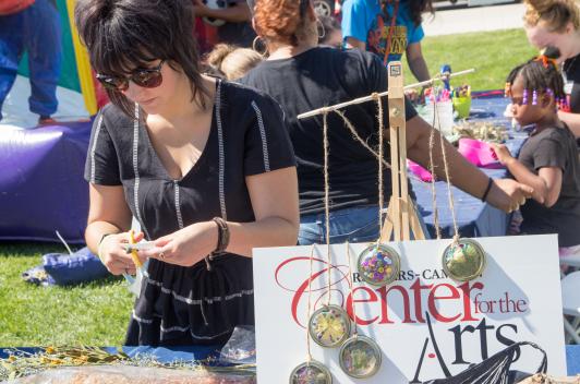 Person at a craft table with a sign saying Center for the Arts