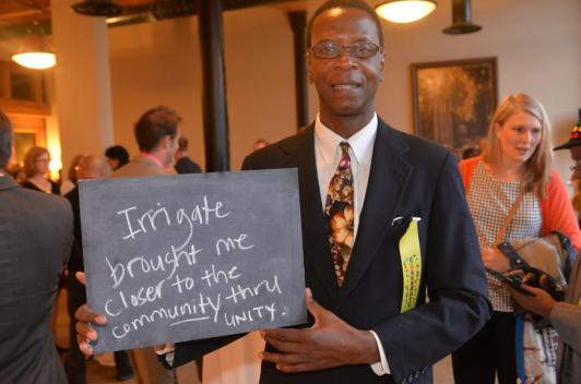 A person holding a chalkboard with the written message "Irrigate brought me closer to the community through unity"