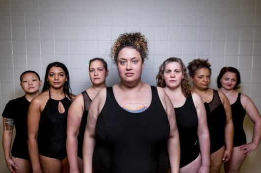 7 swimmers in black swimsuits in a triangle formation.