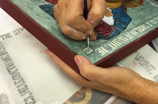 A person hand painting the words on a picture of Jesus