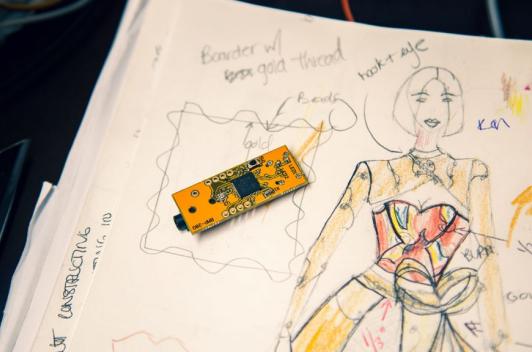 A small microcomputer on top of a sketch of a dress