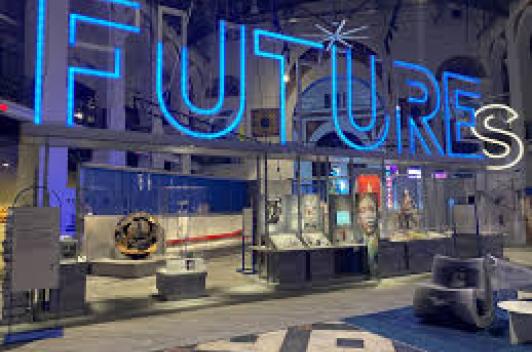 A room filled with various technology displays and a the word FUTURE in blue neon lights