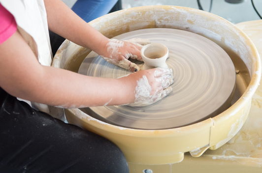 A student spinning pottery on the wheel 