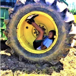 A child sitting inside a tractor wheel