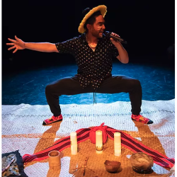 A person stands on top of an embroidered rug that also has candles and a bandana on it.
