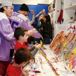 People in sports jackets with children painting on canvas
