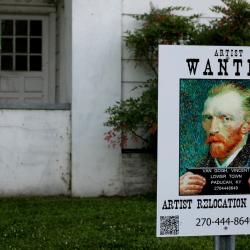 White house with a poster in front saying Wanted and featuring a painting of Van Gogh