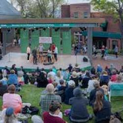 A crowd of people at a green amphitheater watching a play