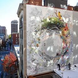 Mural on the side of a building. Mural is a white and grey background with splashes of color in a circle in the middle
