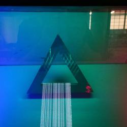 Red, green, and blue light shines on a triangle made of reflective material.
