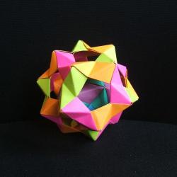 A 4-D origami star. The star is folded with papers of yellow, pink, orange, and purple. There is another, smaller star inside.