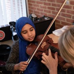 a student with a violin being taught by an instructor