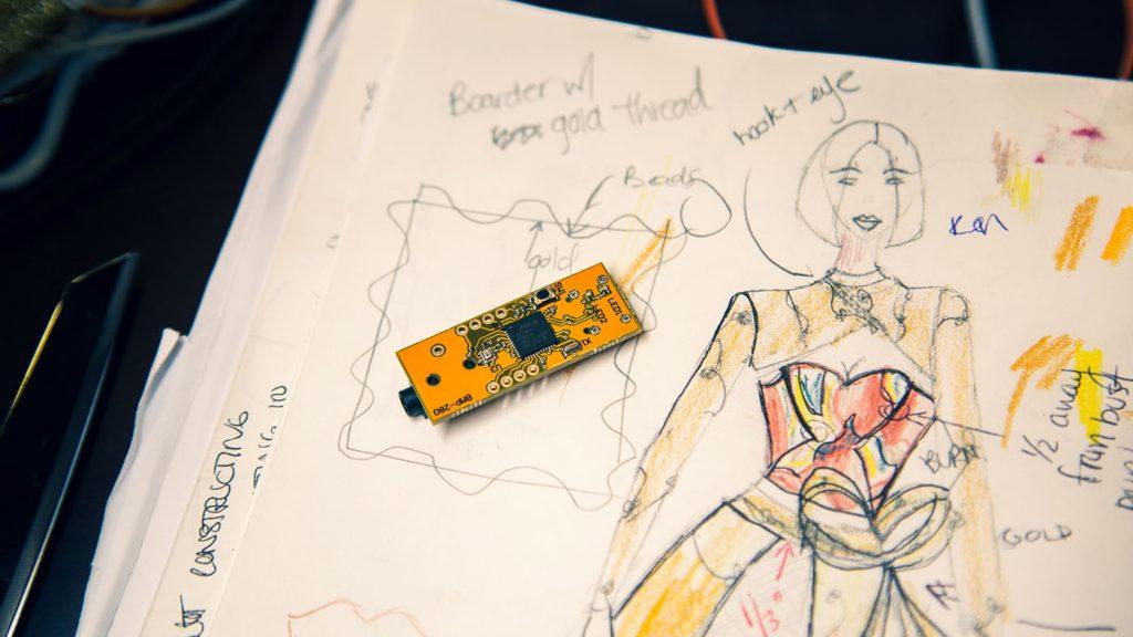 A small microcomputer on top of a sketch of a dress