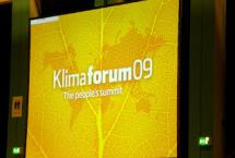 Yellow powerpoint slide with a slightly darker yellow imprint of the world map. The slide features the words Klimaforum09.