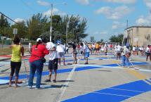 People at an outdoor court repainting it with different colored stripes of blue