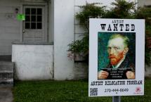 White house with a poster in front saying Wanted and featuring a painting of Van Gogh